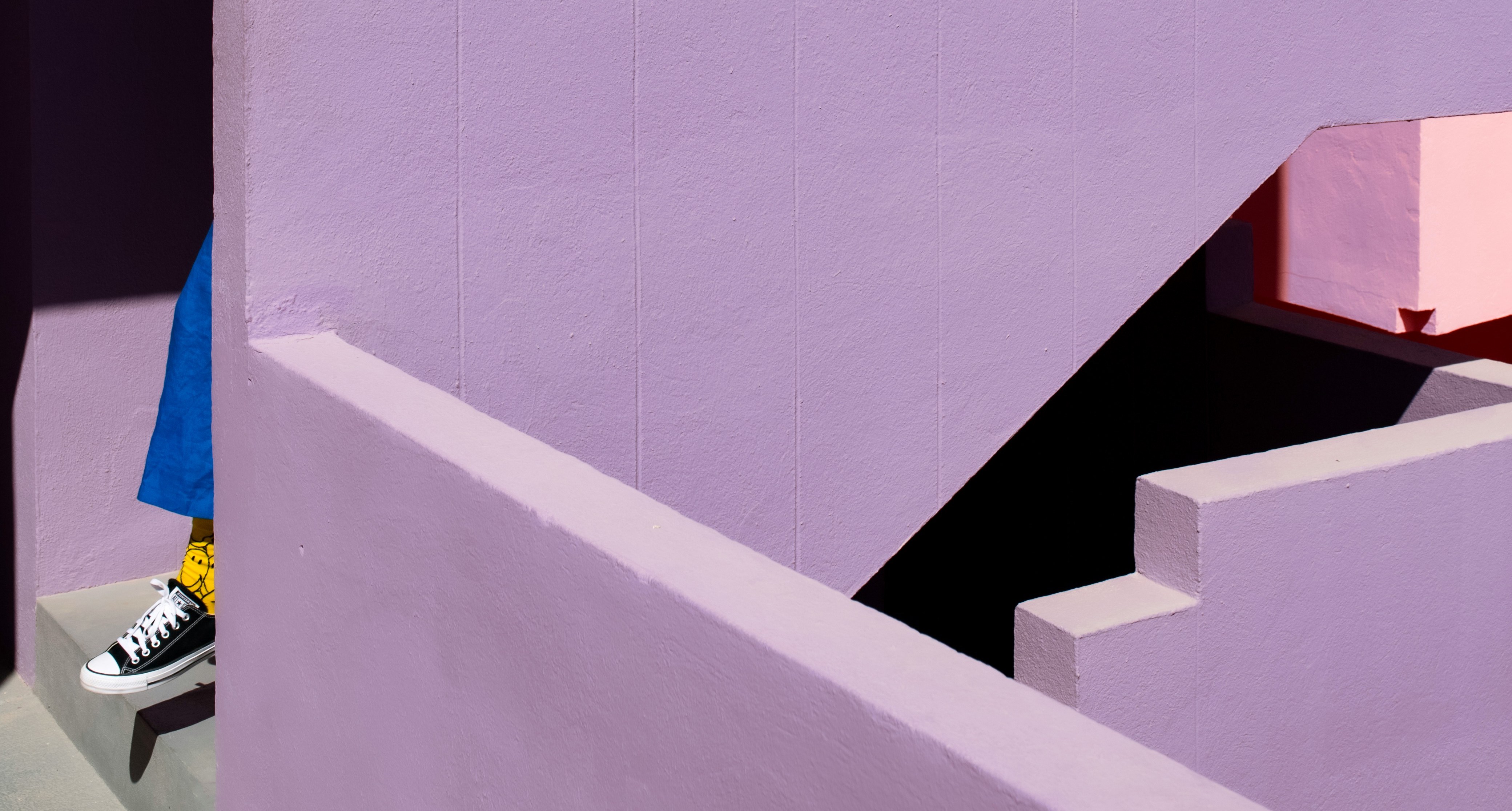 A minimalistic photo with some purple architecture and a person's shoe